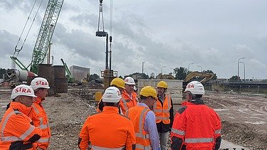 Several people stand in safety clothing on a construction site