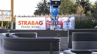 Photo of a 3D printer applying dry mortar in layers to create walls.