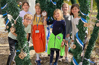 Foto von Schülerinnen und Schüler der Munich International School die den Richtkranz schmücken. 