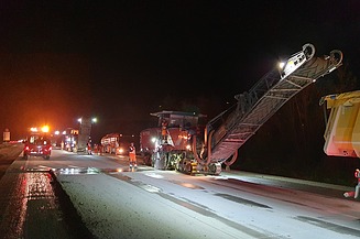 Foto eine Asphaltfräsmaschine im Einsatz bei Nacht im Flutlicht