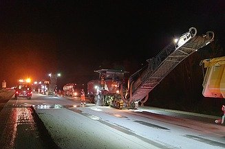 Foto eine Asphaltfräsmaschine im Einsatz bei Nacht im Flutlicht