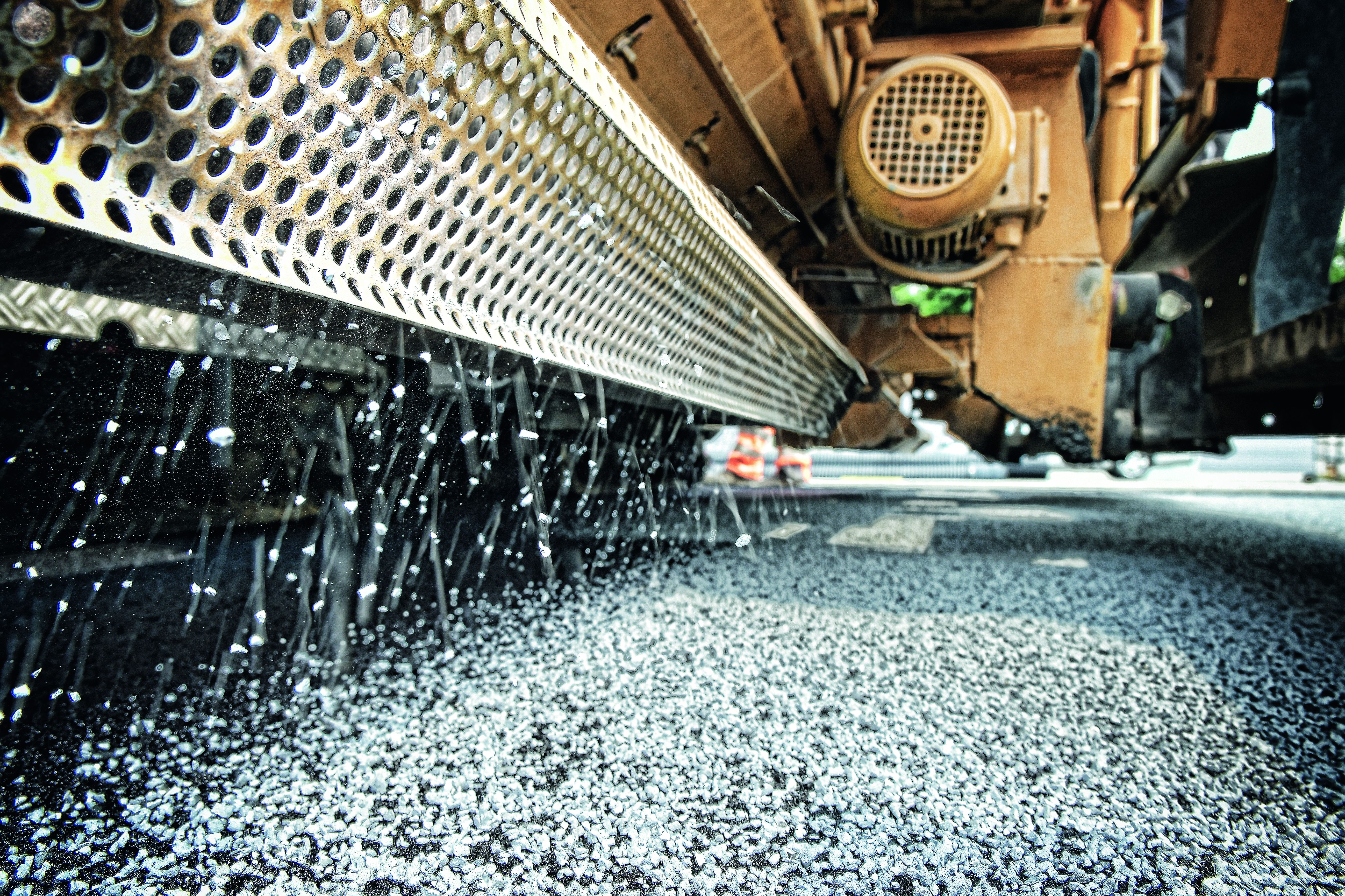 Foto zeigt einen Fertigerintegrierten Streuer im Einsatz