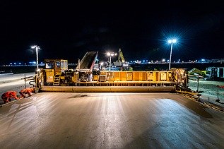 Foto einer gelben Betonbaumaschine bei Nacht bei Flutlicht