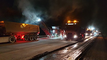 Foto zeigt Fräsarbeiten bei Nacht mit zwei Maschinen und mehreren Fahrzeugen