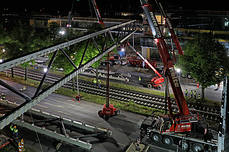 Foto von einer Brücke die grade gebaut wird aus der Vogelperspektive bei Nacht. 