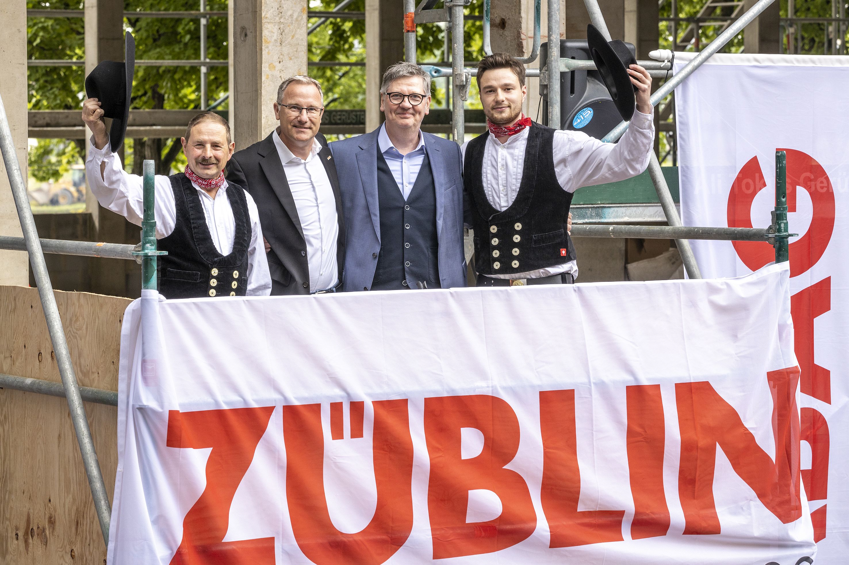 Foto von vier schick gekleideten Männern auf einem Gerüst. 