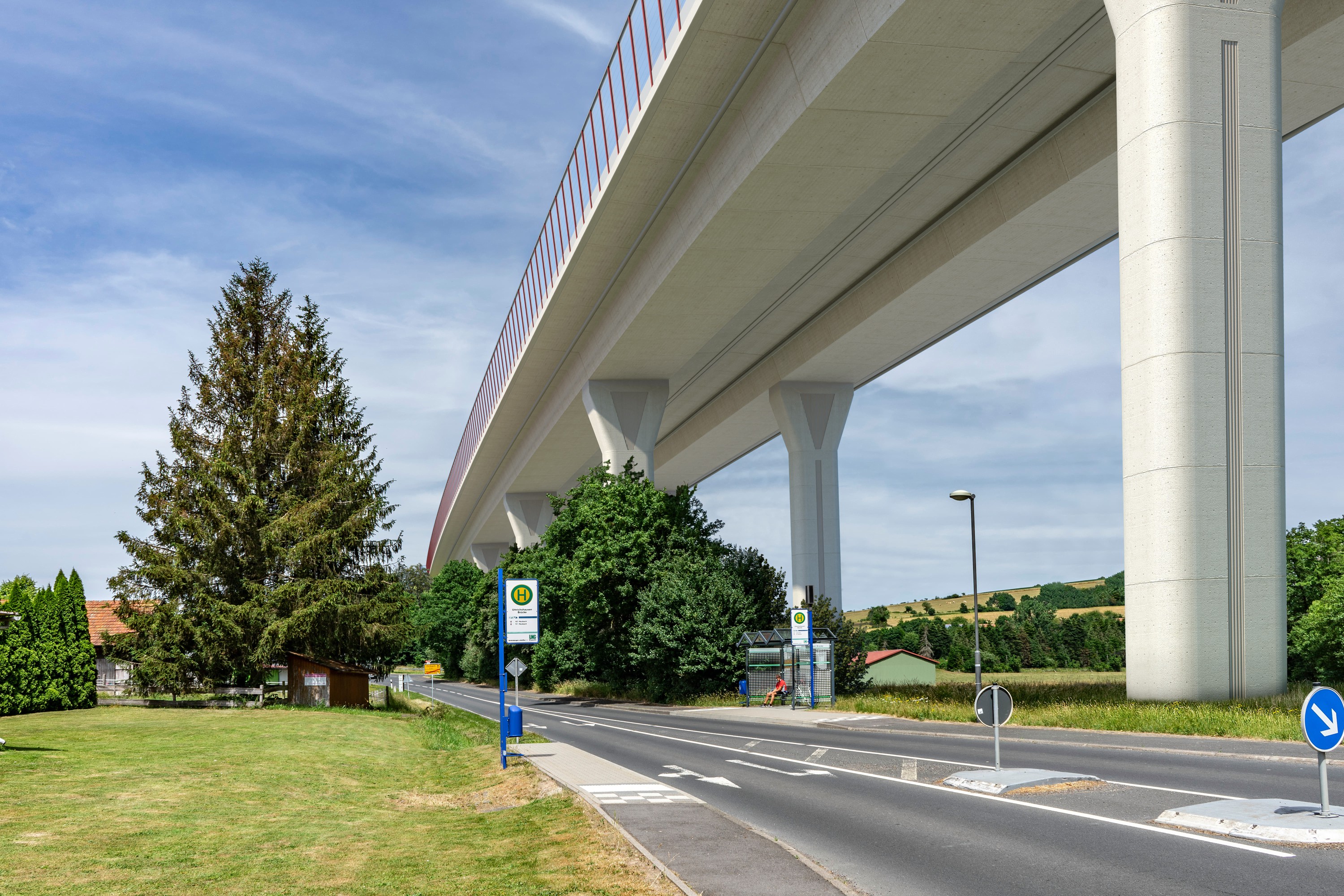 Foto einer neuen Talbrücke von unten gesehen, daneben verläuft eine Landstraße
