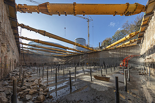 Foto von einem Loch auf einer Baustelle. Am Boden des Lochs sind Metallstäbe. 