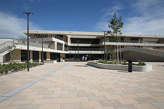 Foto von einem modernen Gebäude bei blauem Himmel, davor ein gepflasterter Platz