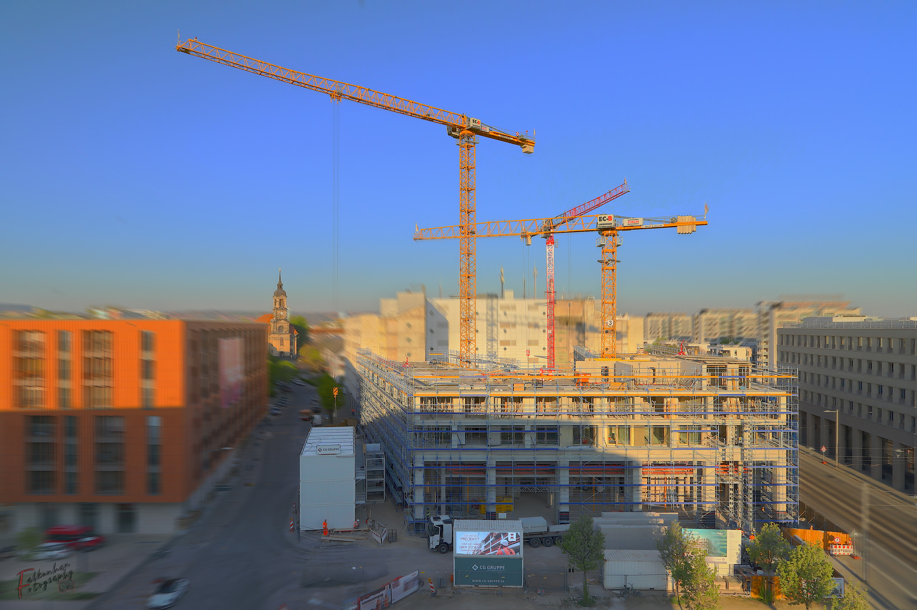 Foto von einer Baustelle für Wohnungen, mit drei Kränen.  