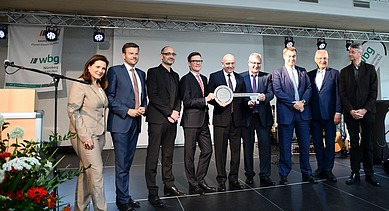 Foto von mehreren Personen, die auf einer Bühne stehen und einen Schlüssel halten. 