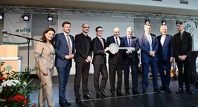 Foto von mehreren Personen, die auf einer Bühne stehen und einen Schlüssel halten. 