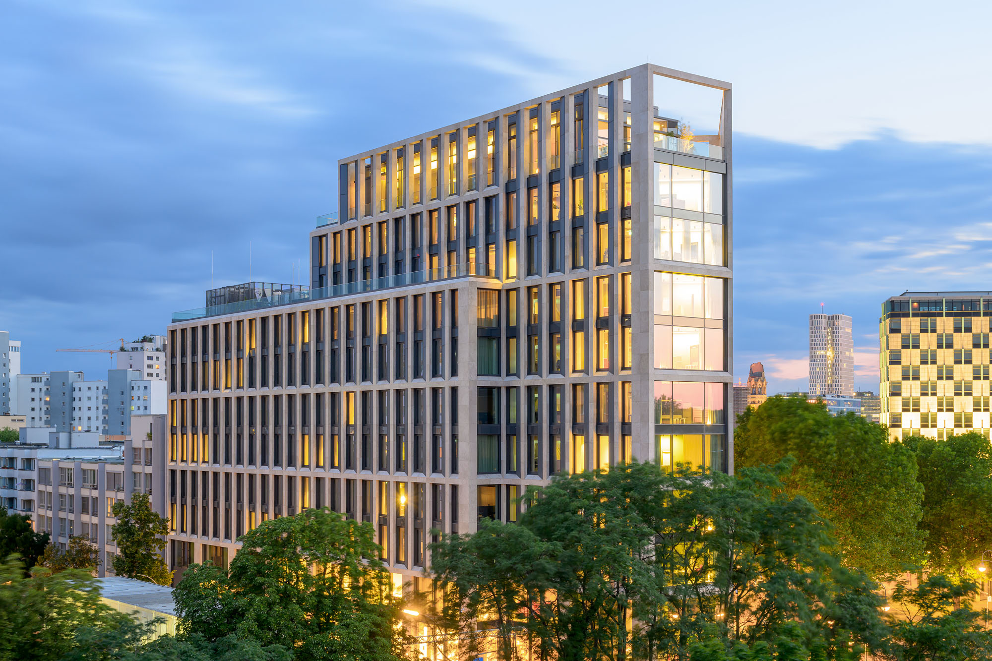 Breites Hochhaus hinter grünen Bäumen