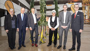 Foto von freundlich schauenden Personen vor dem Richtkranz.