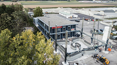 Aerial view of an office building with parking lot, some trees on the right