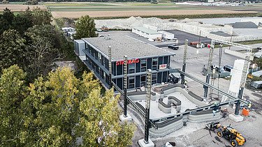 Aerial view of an office building with parking lot, some trees on the right