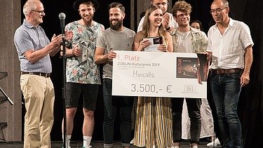Foto von freudig Schauenden Personen auf einer Bühne, die den 1. Platz des ZÜBLIN-Kulturpreis 2019 in der Hand halten.  
