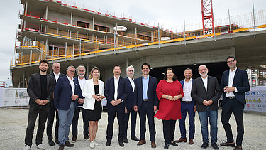 Foto von einer Gleichenfeier, mehrere Personen stehen vor einem Rohbau