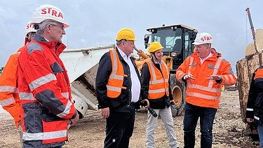 Several people stand in safety clothing on a construction site