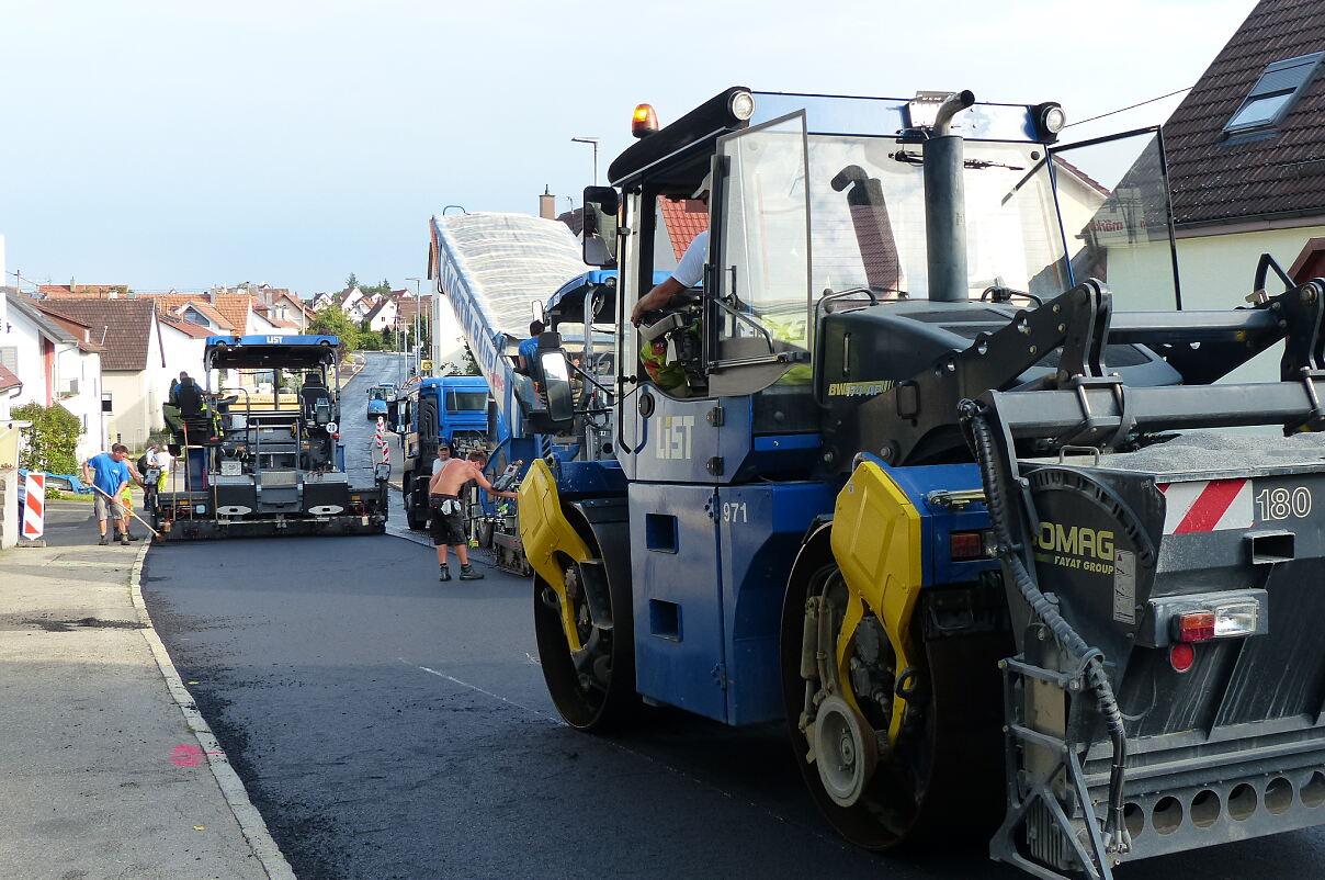 Foto von mehreren Straßenbaumaschinen auf einer frisch asphaltierten Straße
