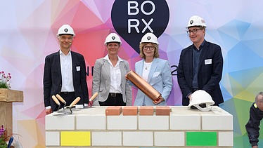 Foto von mehreren Personen die schick gekleidet, sind bei der symbolische Grundsteinlegung für Bürogebäude BORX.