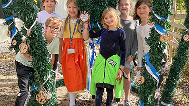 Foto von Schülerinnen und Schüler der Munich International School die den Richtkranz schmücken. 