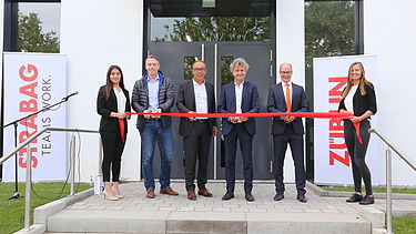 Foto von mehreren Personen bei der Einweihung des neuen Erweiterungsbaus der ZÜBLIN-Direktion in Karlsruhe, die ein rotes Band durchschneiden. 