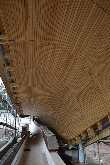 Foto von der Innenansicht einer Rennschlittenbahn mit Holzüberdachung.       