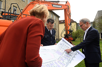 Foto drei Personen die sich Zeichnung anschauen. 