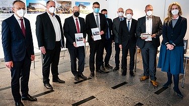 Foto von mehreren, stehenden Personen, die Coronamasken tragen