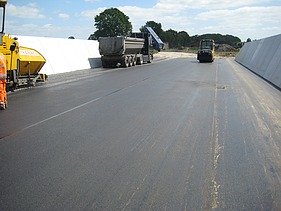 Das Bild zeigt eine Straße mit frischem Walzasphalt