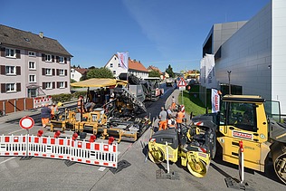 Foto einer Straßenbaustelle im Vordergrund eine weiß-rote Absperrung