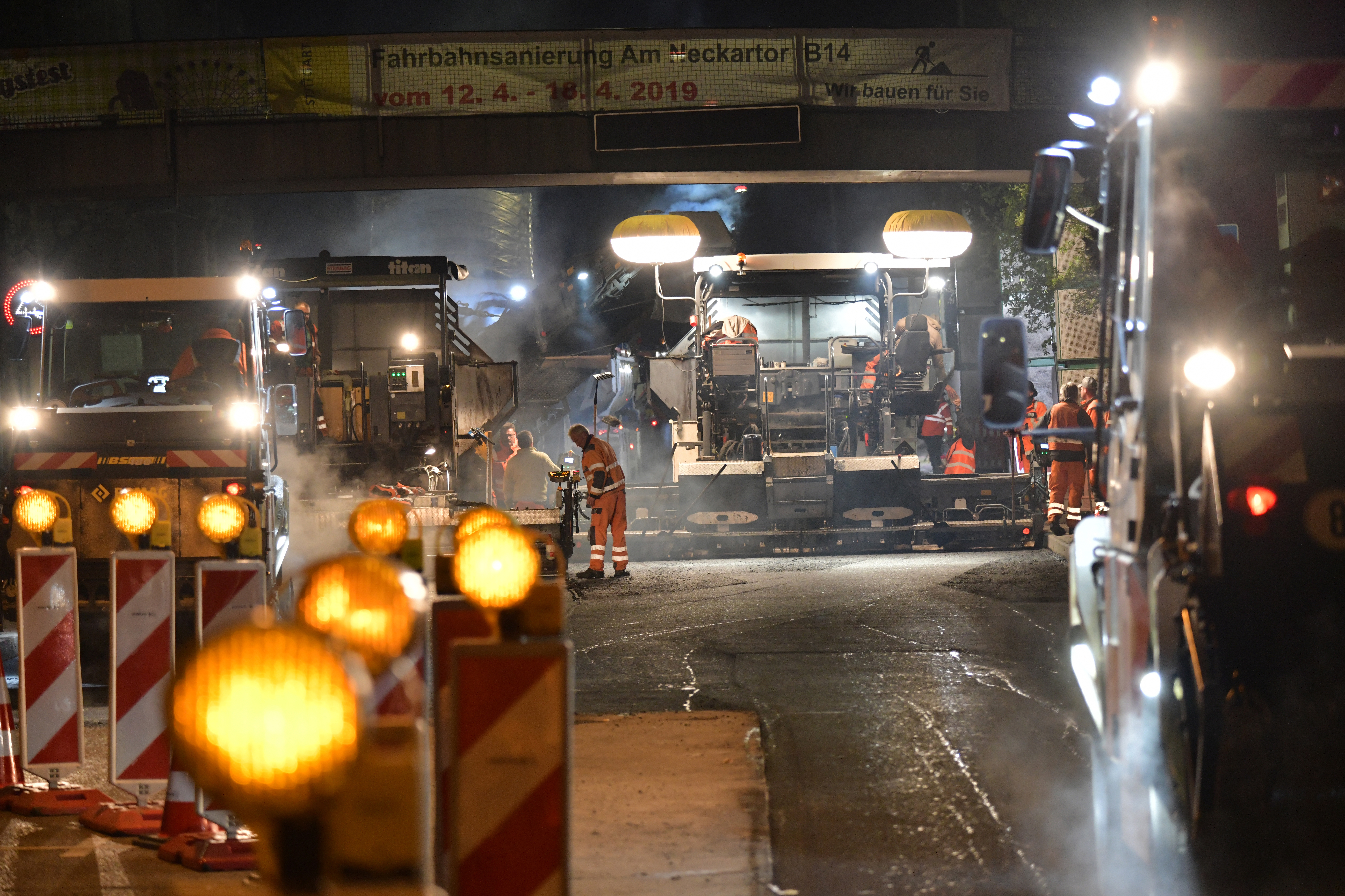 Foto von Straßenbaumaschinen im Einsatz auf einer Fahrbahn bei Nacht