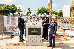 Foto von mehreren Personen, die freundlich schauen bei der Grundsteinlegung. 