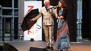 Foto von zwei Personen auf der Bühne. 