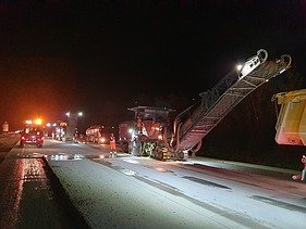 Foto eine Asphaltfräsmaschine im Einsatz bei Nacht im Flutlicht
