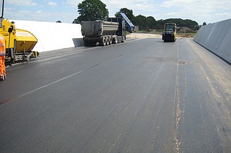 Das Bild zeigt eine Straße mit frischem Walzasphalt