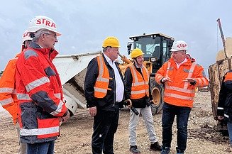 Several people stand in safety clothing on a construction site