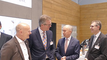 Foto von vier Männern im ZÜBLIN-Stand auf dem Deutschen Bautechniktag 2019 in Stuttgart. Sie lächeln. 