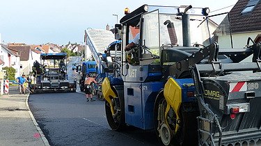 Foto von mehreren Straßenbaumaschinen auf einer frisch asphaltierten Straße