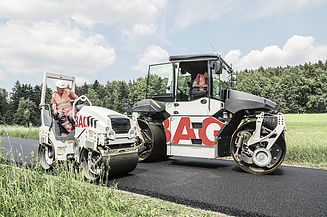 Two construction machines with STRABAG lettering can be seen paving a road after it has been tarred.