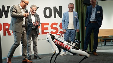 Foto von mehreren Personen, die einen Roboterhund in Aktion zuschauen. 