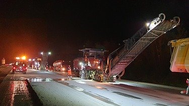 Foto eine Asphaltfräsmaschine im Einsatz bei Nacht im Flutlicht