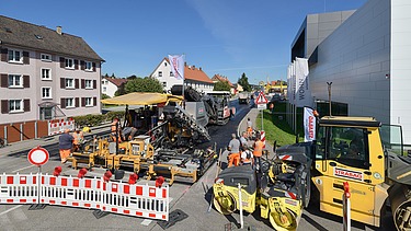 Foto einer Straßenbaustelle im Vordergrund eine weiß-rote Absperrung