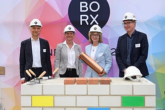 Foto von mehreren Personen die schick gekleidet, sind bei der symbolische Grundsteinlegung für Bürogebäude BORX.
