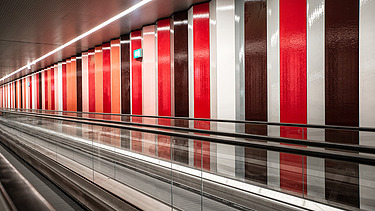 Foto von einer Rolltreppe mit einer bunten Wand.                