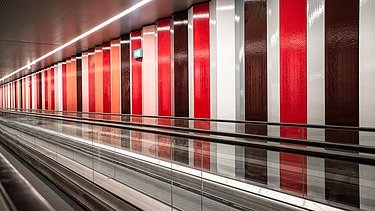 Foto von einer Rolltreppe mit einer bunten Wand.                