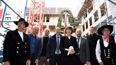 Foto mit der Oberbürgermeisterin von Köln auf der Baustelle im Antoniter Quartier in Köln. Um sie herum sind glück schauende Männer. 