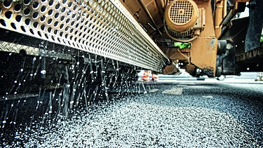 Foto zeigt einen Fertigerintegrierten Streuer im Einsatz