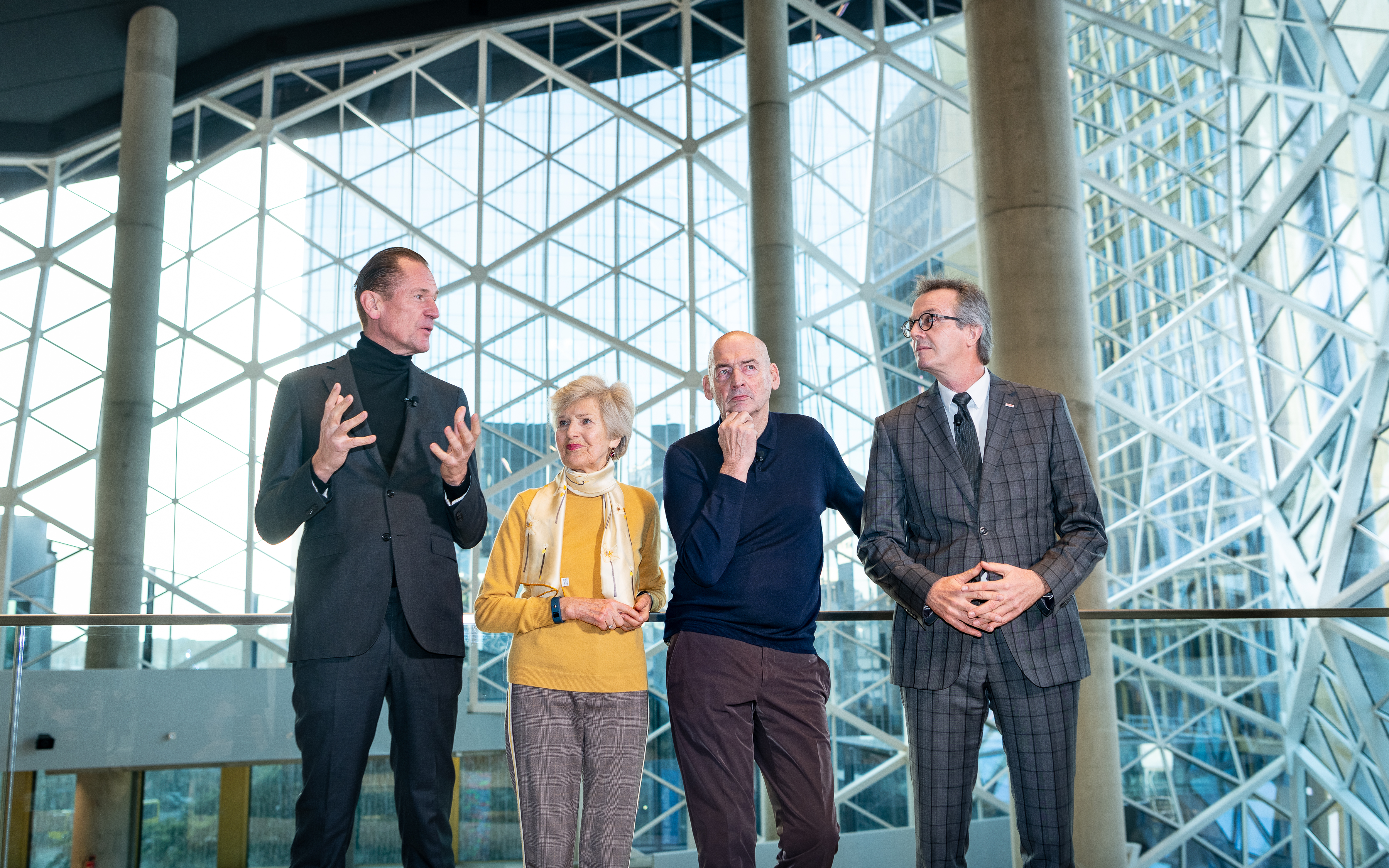 Foto von vier Personen vor einer Glaskuppel, sie schauen nachdenklich.  